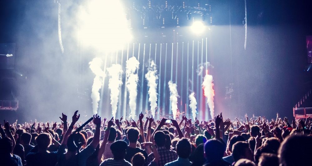 crowd of people waving arms at music festival