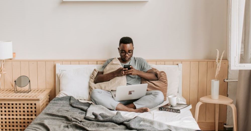 Man sitting on a bed looking at his phone