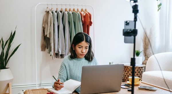 Woman working at laptop with camera set up and clothes