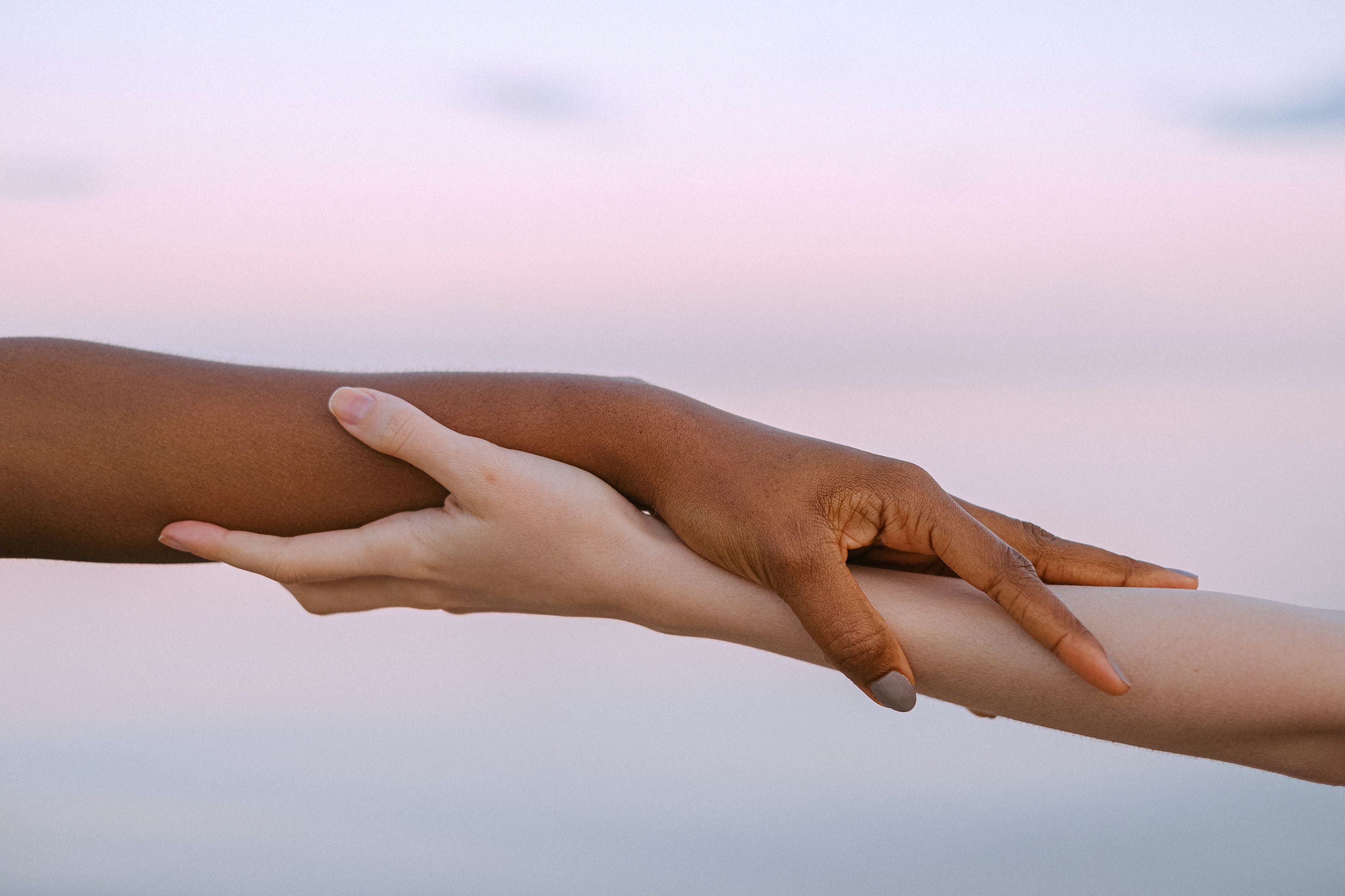 Two hands holding in front of a sunset